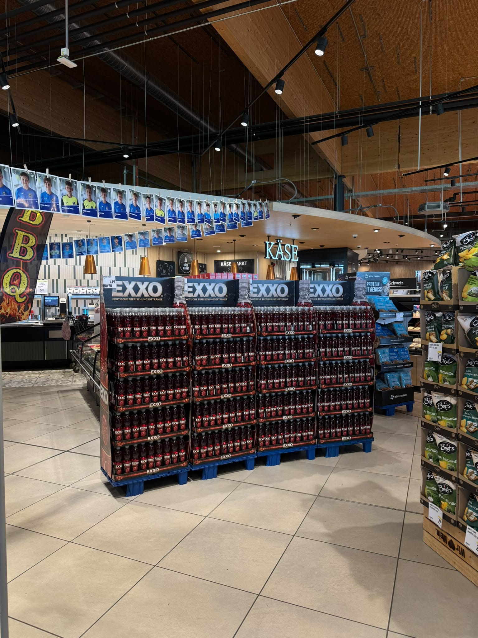 Mehrere EXXO POMA SPRITZ Paletten in Reihe im Mittelgang eines Supermarkts